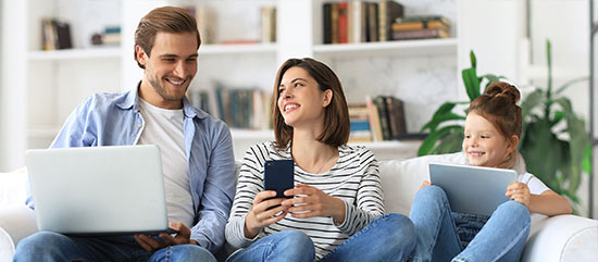 Eine Familie nutzt gemeinsam Laptop, Smartphone und Tablet.