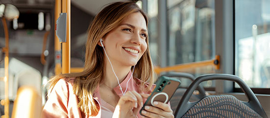 Eine Frau informiert sich unterwegs im Bus auf ihrem Smartphone.