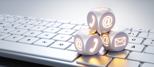 Three illuminated dice with communication  symbols on white keyboard - 3D illustration